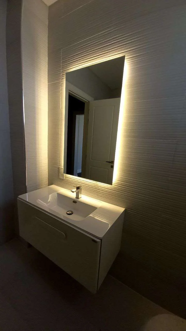 Rectangular backlit mirror above a bathroom vanity