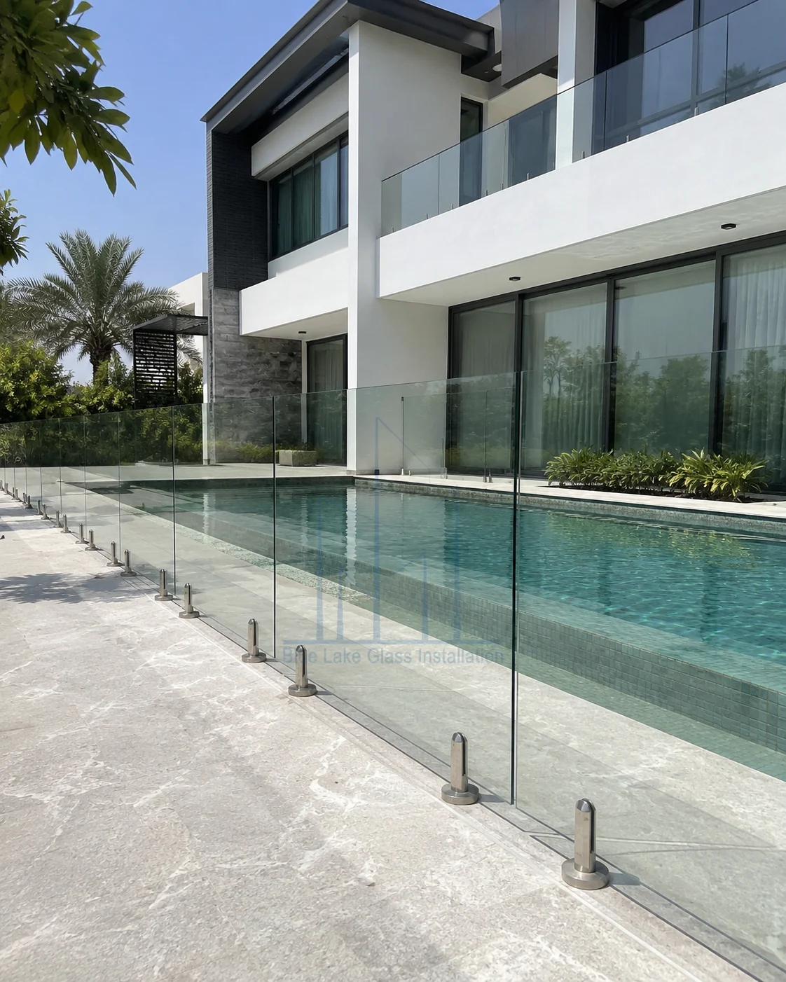 Frameless pool glass fence with stainless steel spigots beside a modern villa